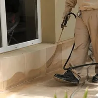 General pest control technician spraying exterior perimeter around a home in Sioux Falls, SD